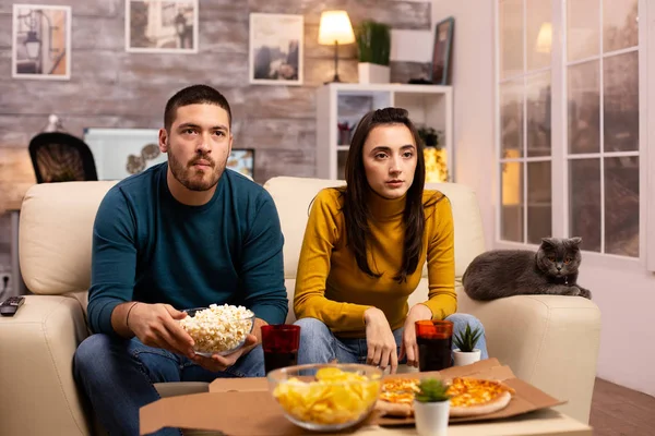 Belo jovem casal assistindo TV e comer fast food takeaway — Fotografia de Stock