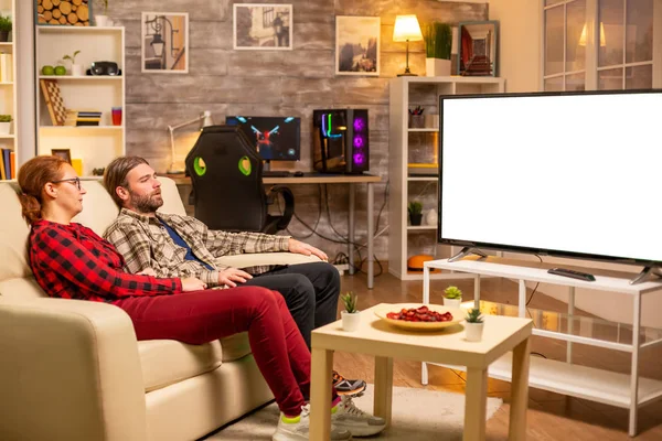 Пара смотрит на белый изолированный экран телевизора поздно ночью в гостиной — стоковое фото
