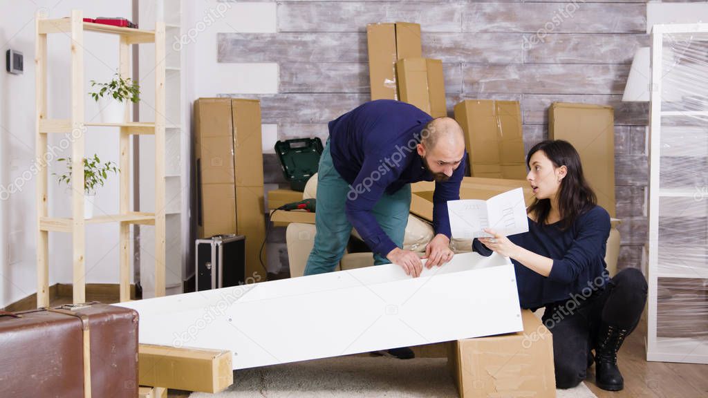 Young couple assembling furniture as a team in new apartment