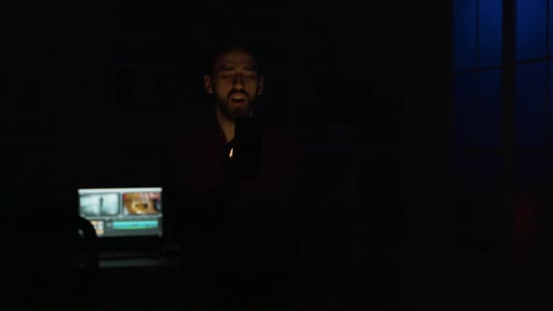 Jongeman geeft een spraakcommando aan zijn slimme lichtapplicatie — Stockvideo