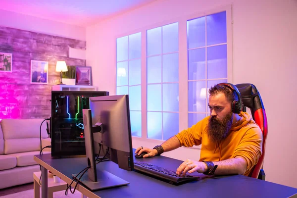 Tiro de tripé estático do homem usando a configuração do pc jogando jogo de  ação online multiplayer conversando com a equipe no fone de ouvido. jogador  sentado na cadeira de jogos transmitindo