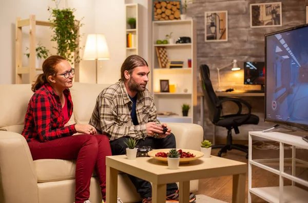 Casal jogando jogos de vídeo na TV de tela grande na sala de estar tarde da noite — Fotografia de Stock