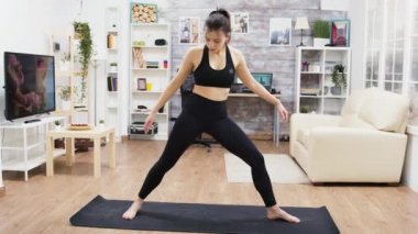 Sakin genç bayan oturma odasında yoga egzersizi yapıyor.