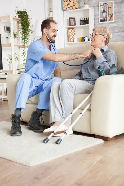 Giovane medico che utilizza lo stetoscopio per ascoltare la vecchia donna battito cardiaco — Foto Stock