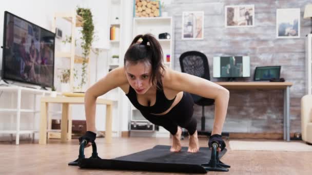 Jonge en sterke vrouw doet push-ups thuis — Stockvideo