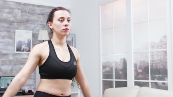 Ung kvinna gör lungor framåt i vardagsrummet — Stockvideo