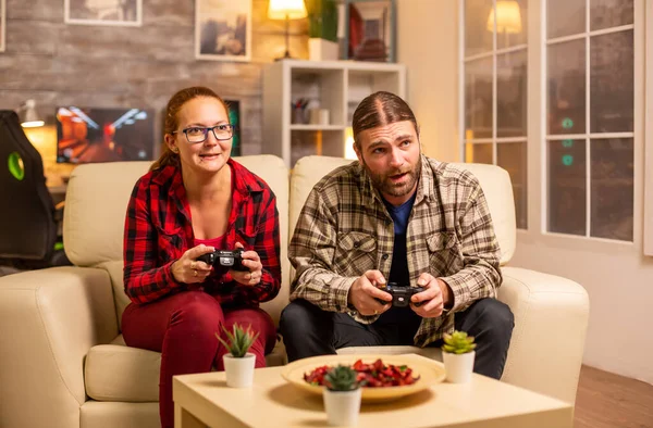 Coppia di giocatori che giocano ai videogiochi in TV con controller wireless in mano — Foto Stock