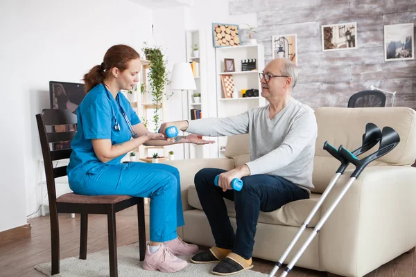 Жіноча медсестра сидить на стільці допомагаючи старшому чоловікові — стокове фото