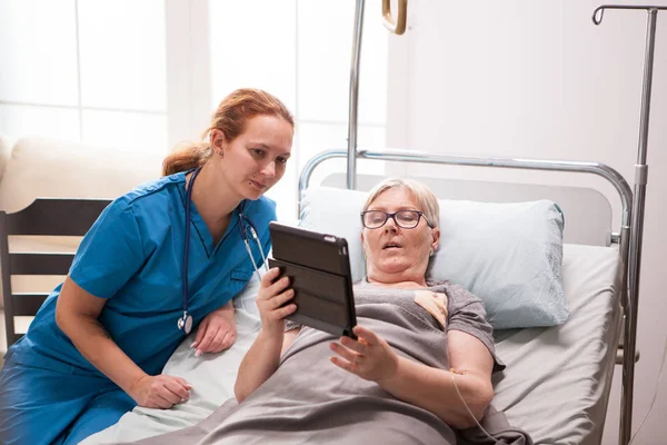 Portrét staré ženy v pečovatelském domě pomocí tabletu počítače — Stock fotografie