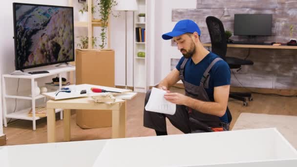 Ung manlig arbetare monteringsdetaljer av möbler i nytt hem — Stockvideo