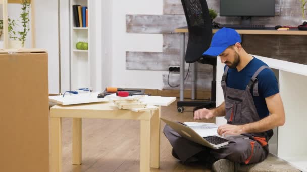 Möbelmonteur benutzt Laptop, um Anweisungen einzusehen — Stockvideo