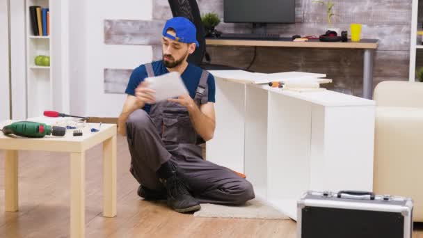 Zoom in shot of man in overalls assembles a shelf — ストック動画