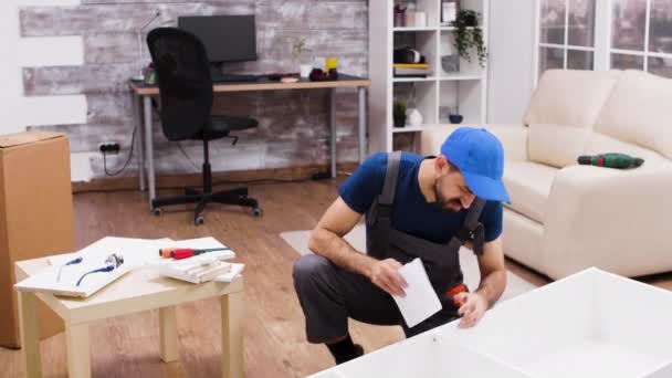 Bělošský pracovník vypadá zmateně v návodu na montáž nábytku — Stock video