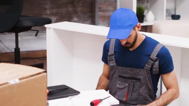 Close up of young man in coverall using laptop to assembly furniture — Stok video