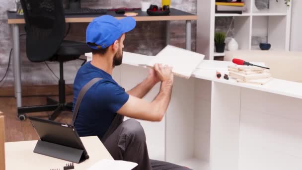 Рабочий мужчина, следуя инструкциям по мебели из планшета — стоковое видео