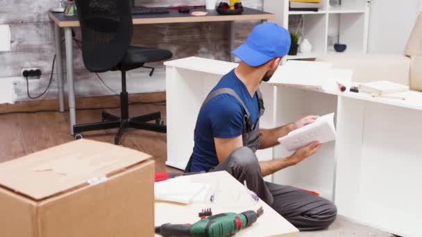 Hombre trabajador en bata sentado en el suelo siguiendo las instrucciones — Vídeo de stock