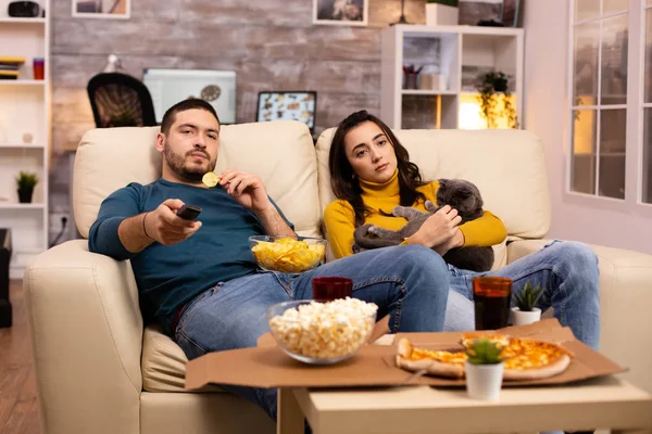Schönes junges Paar schaut fern und isst Fast Food zum Mitnehmen — Stockfoto