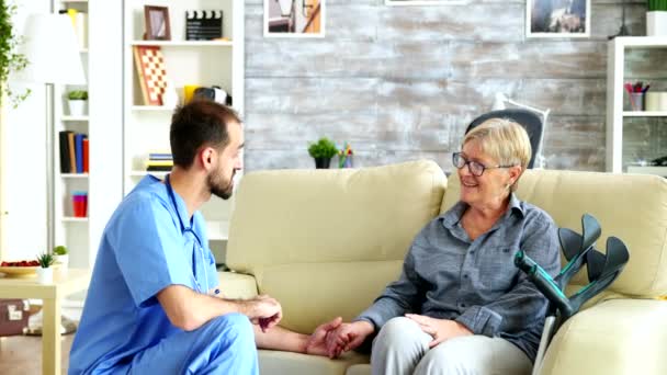 Muž zdravotní sestra držení staré ženy ruku v pečovatelském domě — Stock video