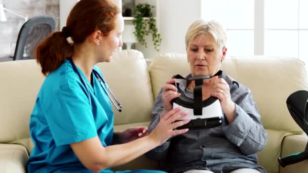 Жіноча медсестра допомагає старшій жінці відчути віртуальну реальність — стокове відео