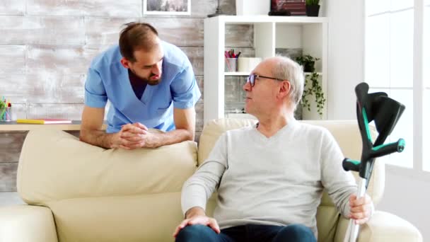 Elderly man having a conversation with a male nurse in cozy nursing home — Stock Video