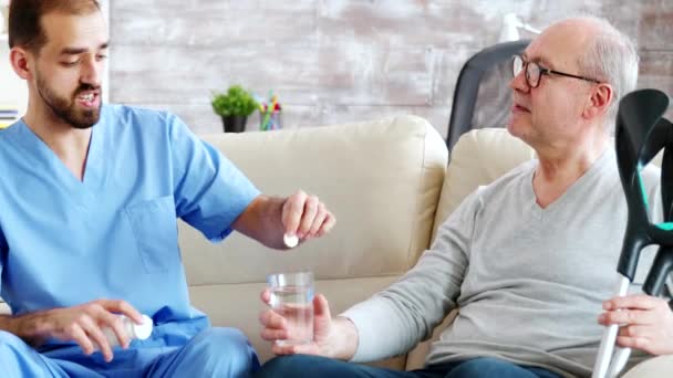 Mannelijke verpleegster geeft pillen aan gepensioneerde man in verpleeghuis — Stockvideo