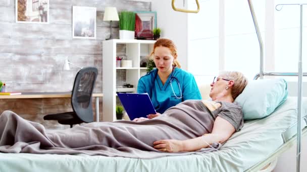 为躺在病床上的老年残疾妇女提供咨询的社工 — 图库视频影像