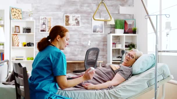 Caucasian nurse showing an old lady the pills dosage she supposed to take — Stock Video