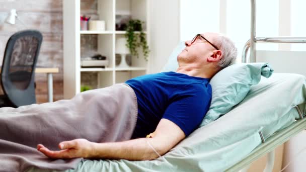 Portrait of elderly sick man lying in hospital bed — Stock Video