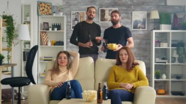 Bir grup arkadaş oturma odasında futbol maçı izliyor.