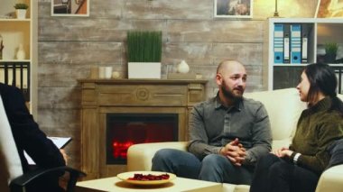 Genç çift terapide kanepede oturup birbirlerine sarılıyorlar.