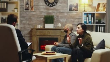 Angry wife on sofa at couple therapy yelling