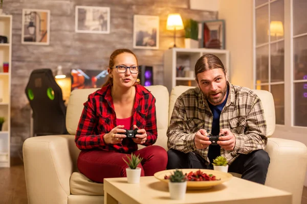 Hráči pár hraje videohry na televizoru s bezdrátovými ovladači v rukou — Stock fotografie
