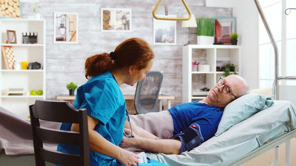 Female nurse checking old sick man blood pressure — 스톡 사진