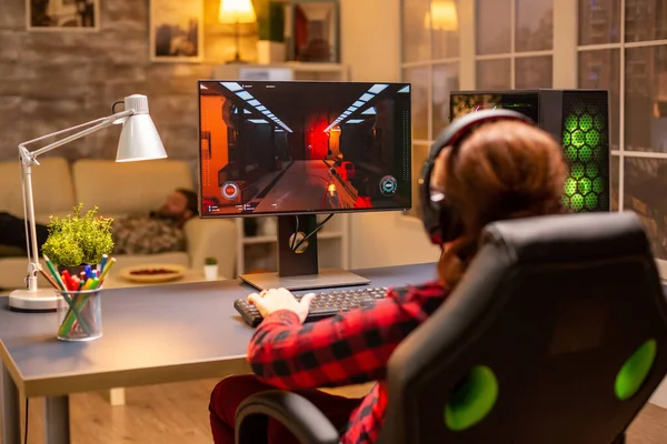 Widok z tyłu żeńskiego gracza grającego na potężnym komputerze PC późno w nocy w salonie — Zdjęcie stockowe