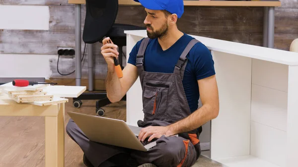 Furniture assembly worker wearing overalls searching instructions