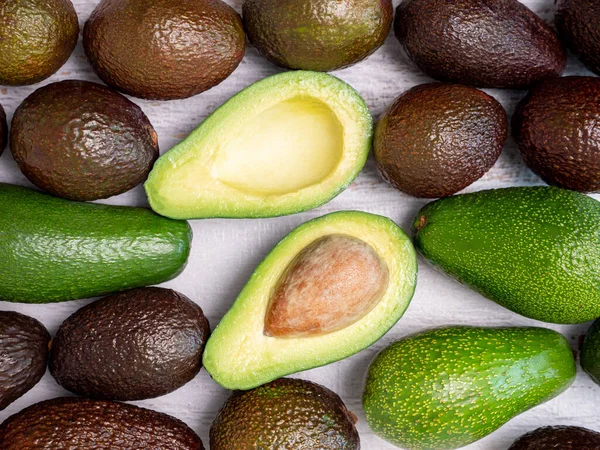 Mezcla de aguacates rasgados y verdes sobre tabla de madera blanca — Foto de Stock