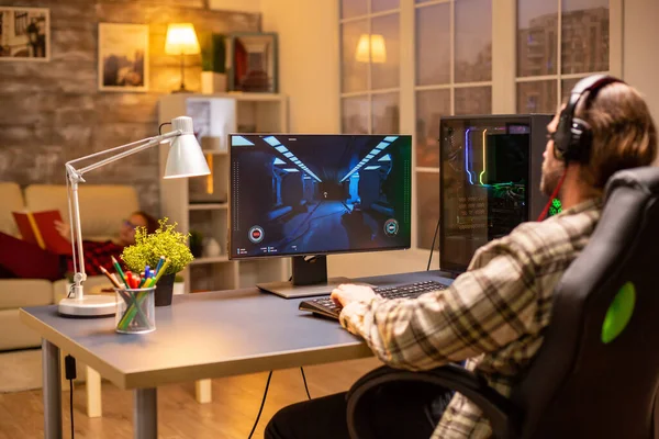 Achteraanzicht van gamer man spelen van een schutter op zijn krachtige PC computer laat in de avond in de woonkamer — Stockfoto