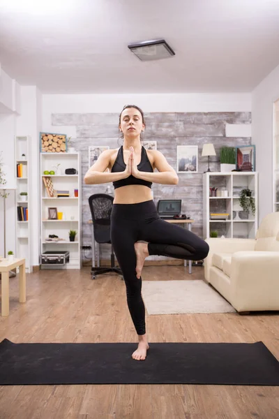 Bella giovane donna con gli occhi chiusi praticando albero yoga posa — Foto Stock