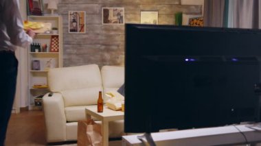 Kravatlı bir iş adamı pizza yiyor ve televizyon izliyor.