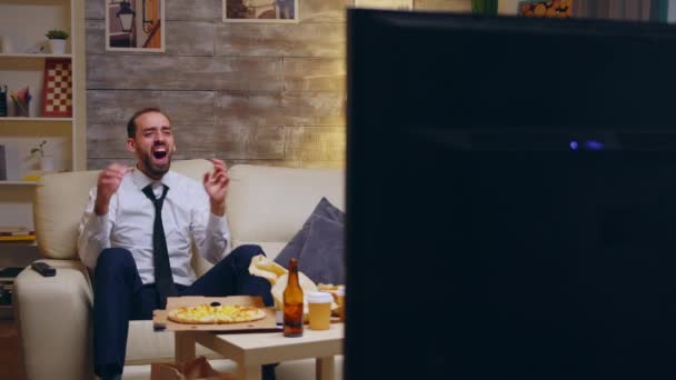 Уставший бизнесмен в костюме сидит на диване и смеется — стоковое видео