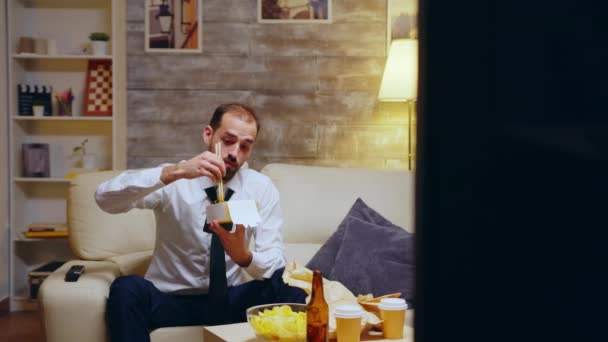 Empresário com gravata comer macarrão sentado no sofá — Vídeo de Stock