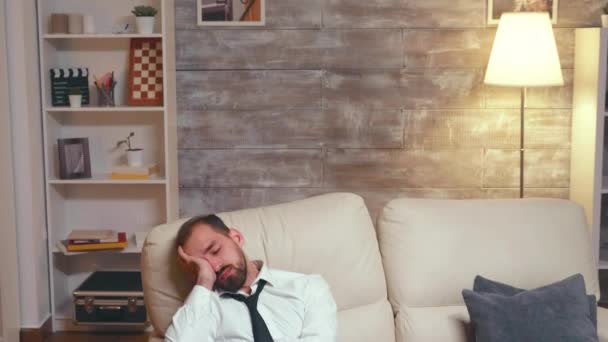 Перегруженный работой бизнесмен спит на диване — стоковое видео