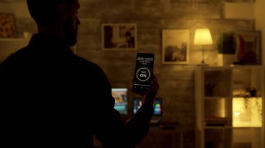 Adam evdeki ışıkları açmak için akıllı telefonunda ses etkinleştirilmiş akıllı ışık uygulaması kullanıyor.