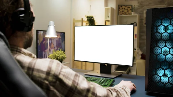 Muž se sluchátky hrát hry na počítači se zelenou obrazovkou — Stock fotografie