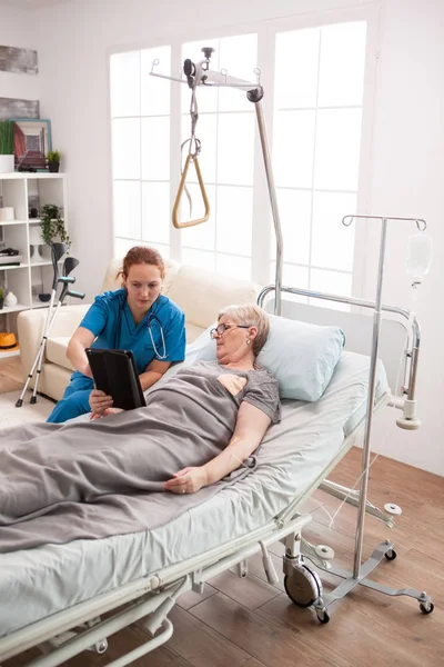 Custode femminile e donna anziana utilizzando tablet — Foto Stock