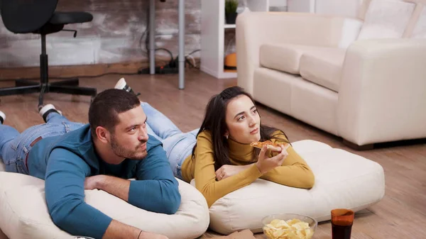 Mladý muž a žena leželi na podlaze a dívali se na televizi — Stock fotografie