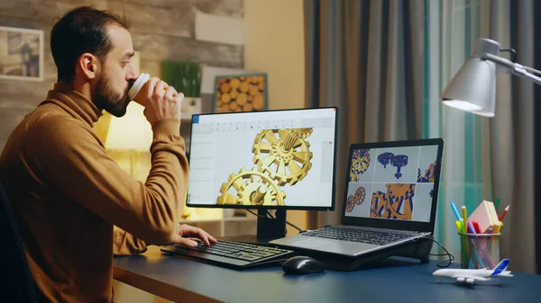 Bearded engineer taking a sip of coffee while working on computer — Zdjęcie stockowe