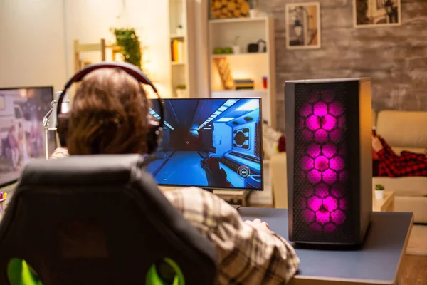 Achteraanzicht van gamer man spelen van een schutter op zijn krachtige PC computer laat in de avond in de woonkamer — Stockfoto