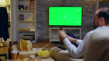 Back view of young entrepreneur relaxing watching tv