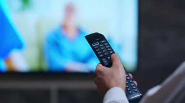 Back view of businessman using tv remote control